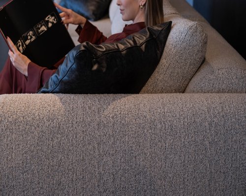 Person relaxing and reading a book on a comfortable sofa in the evening